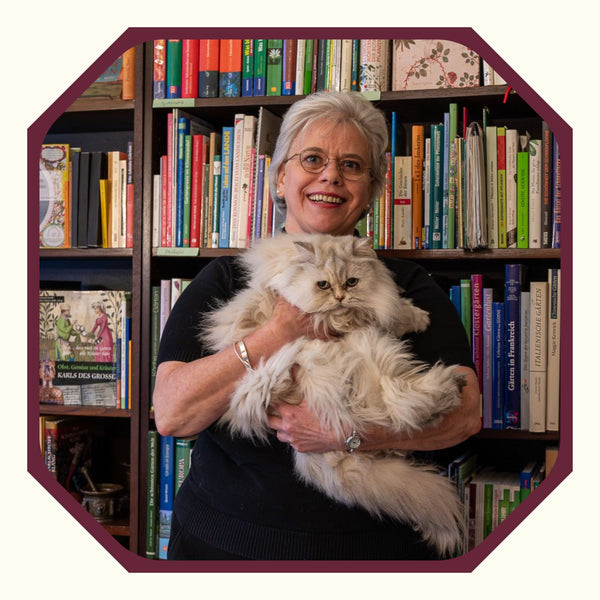 Lydia Pokall mit Katze vor ihrem Bücherregal